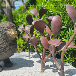 一株株銅葉舒展枝姿，在陽光下閃耀生命的光澤，鳥兒靜靜守望，為街道增添自然的詩意。