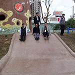 新業(yè)建設(shè)卓勝隆董事長(中)與來賓童心大發(fā)，一起玩溜滑梯。