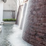 與接待大廳相對，僅隔一道玻璃落地窗即為「戶外水瀑牆」。流水潺潺與磚石沖刷出平整的紋路，水光相映下霧氣生騰，彷若仙境。－【新業(yè)觀峰】。