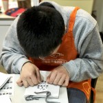 小羊苗朋友將臉湊近提袋上，仔細(xì)將貼紙慢慢地貼上，盡可能確保貼紙有貼正不歪斜。從肢體動作，可以曉得小羊們做每件事比別人費力，但不減心意。