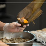 將粽葉三分之一處折起，交叉形成漏斗狀，轉(zhuǎn)著處末端折一個(gè)折角，再將內(nèi)餡包入。