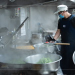 早上六點(diǎn)開始，中央廚房與志工著手備餐，馬不停蹄的來回穿梭，從打菜到分裝都與時(shí)間賽跑著，每個流程都是滿滿的真心與付出。