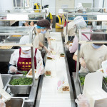 新業(yè)同仁與甘霖志工們分工合作，以生產(chǎn)線的方式有序地進(jìn)行，將熱騰騰的餐食迅速裝盒，確保長輩能準(zhǔn)時(shí)享用午餐。